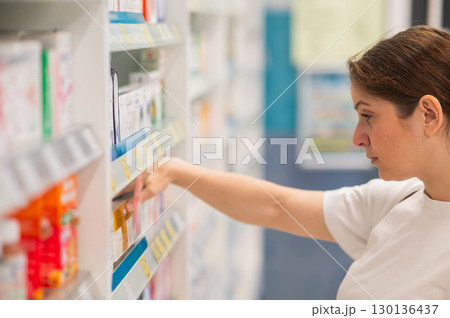 Caucasian woman choosing medicines in a pharmacy.  130136437