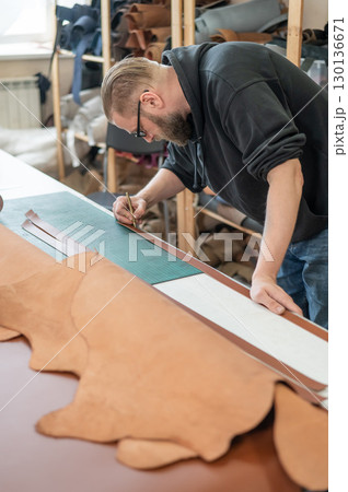 Caucasian bearded man working as a tanner in a workshop.  130136671