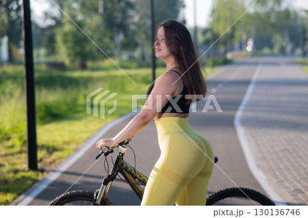 Curvy Caucasian Woman Riding Bicycle in Park.  130136746