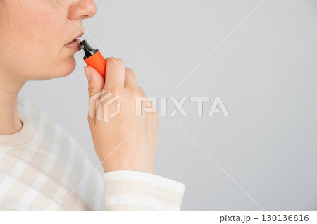 Caucasian woman smoking disposable vape.  130136816