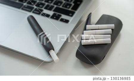 Tobacco heating system next to a laptop. Tobacco heating system next to a laptop. 130136985