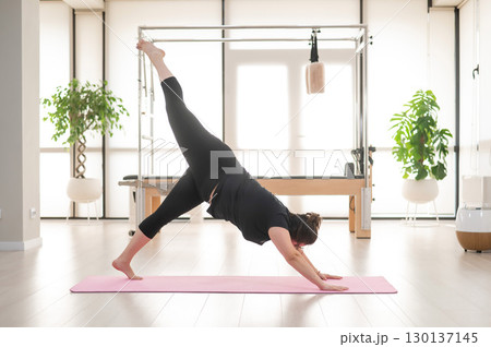 A plump woman does Pilates in a studio.  130137145