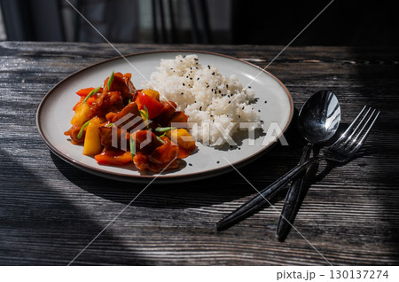Pork in sweet and sour sauce with boiled rice on a plate. Pork in sweet and sour sauce with boiled rice on a plate. 130137274