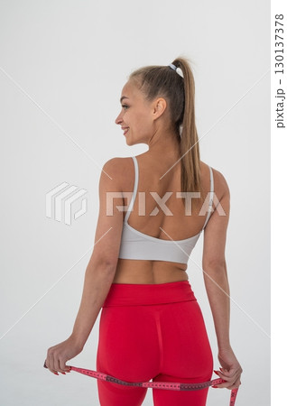 Young woman measuring her hips circumference on white background. 130137378