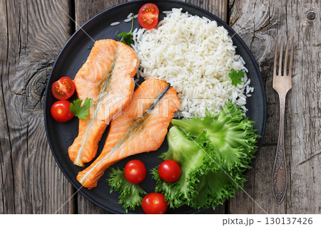 baked salmon steaks with rice, lettuce, tomatoes baked salmon steaks with rice, lettuce, tomatoes 130137426