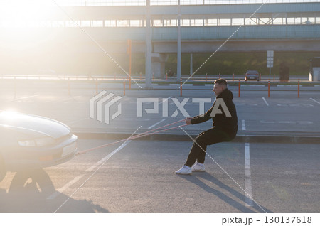 Caucasian man pulling a car with a rope. Caucasian man pulling a car with a rope. 130137618