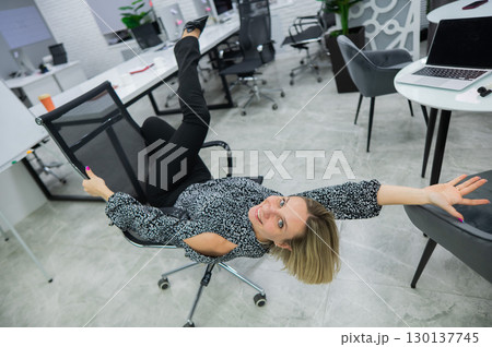 Caucasian woman having fun and lying on office chair. Caucasian woman having fun and lying on office chair. 130137745