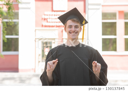 Caucasian young man in graduation gown communicating using sign language.  130137845