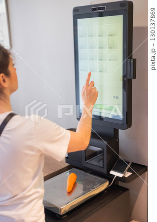 Woman weighing a lemon at a self-checkout. Woman weighing a lemon at a self-checkout. 130137869