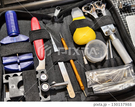 Close up of watch repair tools and wristwatch on black grid background. Close up of watch repair tools and wristwatch on black grid background. 130137988