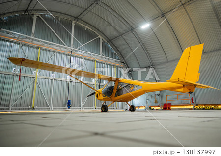 Yellow airplane glider in the hangar.  130137997