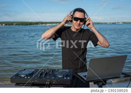 Male DJ playing music on the beach.  130138020