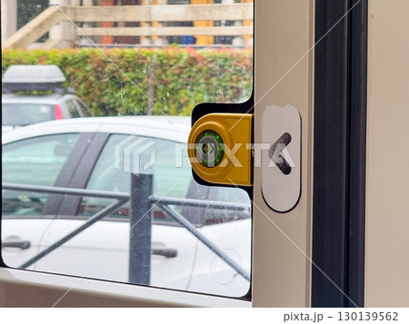 Yellow button with green light for tram door opening on glass surface with arrow symbol. Public transport, service, infrastructure, passenger access and technology. 130139562