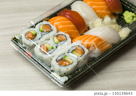 Fresh sushi platter with salmon nigiri and avocado rolls in clear takeout container Fresh sushi platter with salmon nigiri and avocado rolls in clear takeout container 130139643