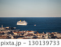 Luxury cruise ship anchored in deep blue Mediterranean waters near historic coastal Trieste city with terracotta rooftops 130139733
