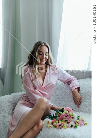 Blonde smiling in summer dress with bouquet of spring flowers 130140161