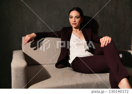 woman in business suit sitting on gray office sofa 130140172