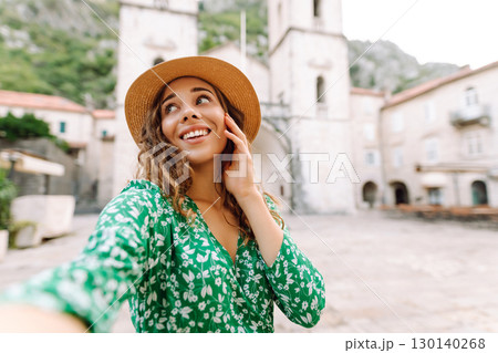 Beautiful woman walks the streets and takes selfie using smartphone camera. Blogging, lifestyle 130140268
