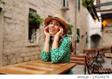 Young woman sitting by table of outdoor sidewalk cafe restaurant. People, fashion, lifestyle 130140270