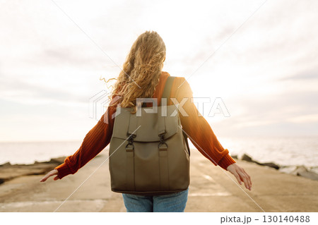 Portrait of woman enjoying a breezy day near a vibrant red lighthouse at sunset. Lifestyle concept. Portrait of woman enjoying a breezy day near a vibrant red lighthouse at sunset. Lifestyle concept. 130140488
