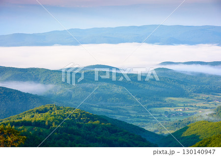 rural landscape with fog in summer. green meadow on the hill in morning light. beautiful countryside in carpathian mountains under blue sky with clouds. scenic view rural landscape with fog in summer. green meadow on the hill in morning light. beautiful countryside in carpathian mountains under blue sky with clouds. scenic view 130140947