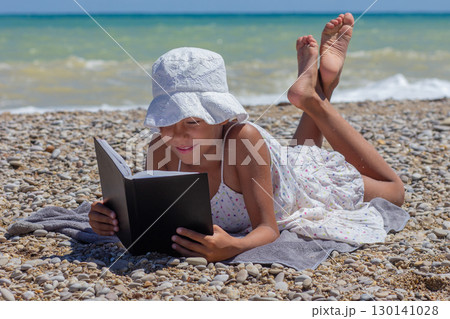 Child absorbed in a book on a rocky beach Child absorbed in a book on a rocky beach 130141028