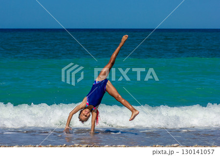 Girl Doing a Cartwheel on the Beach 130141057
