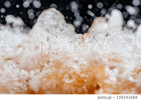 Dynamic splash of beer captured in mid-air on black, perfect for backgrounds 130141688
