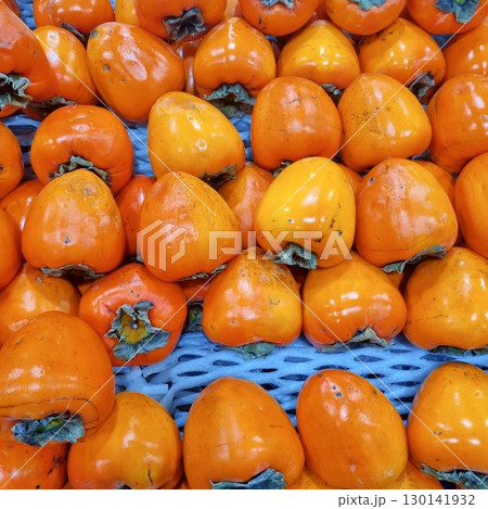 The images show large, cone-shaped persimmons, known as 'daebong' or hachiya persimmons, arranged for sale. They are typically astringent until fully ripe and soft. 130141932