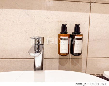 Wall-mounted soap and shampoo dispensers in hotel bathroom. Hygiene, sanitation, and service in modern hospitality. 130141974