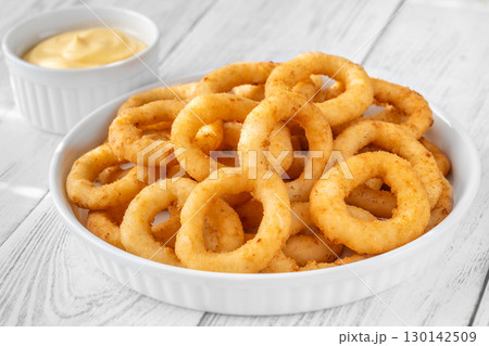 Crispy onion rings with cheese sauce on white plate and table 130142509