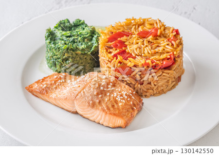 Elegant plated salmon with rice pilaf and creamy spinach on white round plate 130142550
