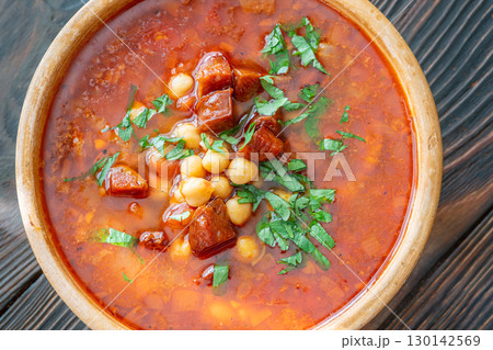 Rustic bowl of Spanish chorizo tomato chickpeas soup topped with cilantro Rustic bowl of Spanish chorizo tomato chickpeas soup topped with cilantro 130142569