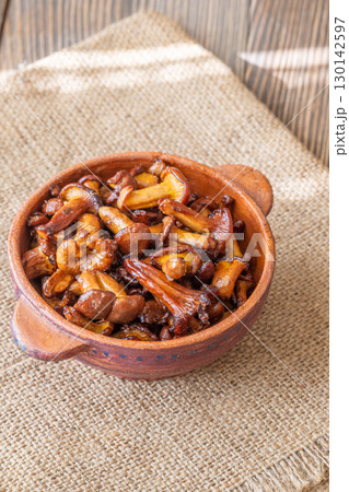 Rustic bowl filled with golden fried chanterelle mushrooms on table Rustic bowl filled with golden fried chanterelle mushrooms on table 130142597