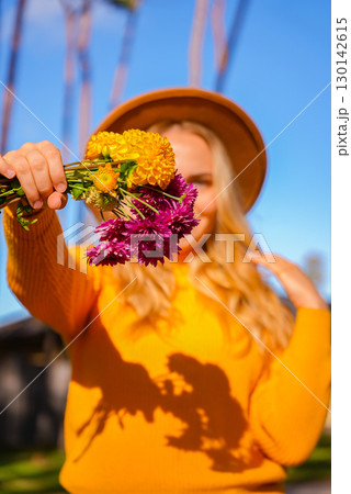 Woman showing into camera Autumn garden colorful flowers. Beautiful autumnal bouquet dahlia chrysanthemum. Red pink orange fall color fall floral background. Flower shop and florist design concept 130142615