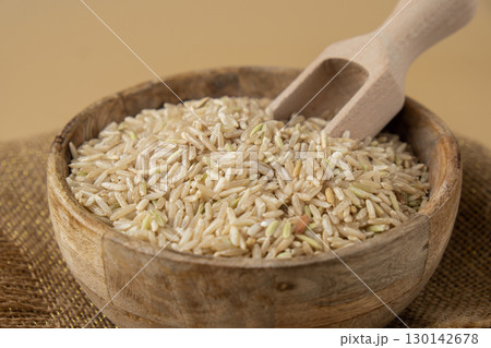 Brown rice in neutral beige background copy space. Whole spelt grain species. High protein fiber-rich vegan plant based food ingredient. Gluten free superfood healthy nutritional dietary alternative 130142678