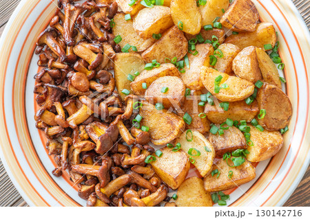 Fried potatoes chanterelle mushrooms seasoned paprika rustic wooden table plate Fried potatoes chanterelle mushrooms seasoned paprika rustic wooden table plate 130142716