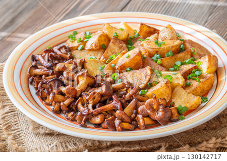 Fried potatoes chanterelle mushrooms seasoned paprika rustic wooden table plate 130142717