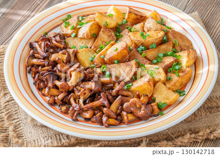 Fried potatoes chanterelle mushrooms seasoned paprika rustic wooden table plate 130142718