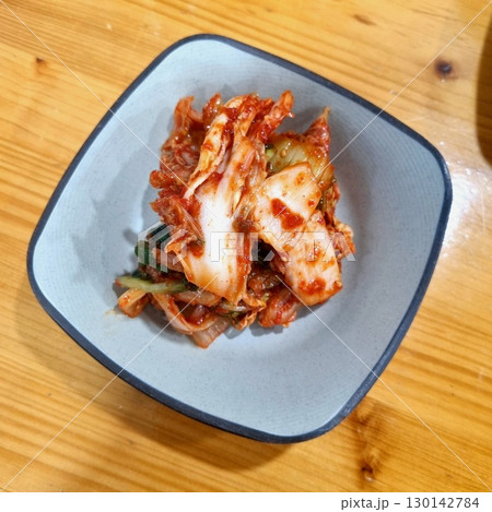 The images show a small bowl of kimchi, a classic Korean side dish of fermented and spiced napa cabbage. The images show a small bowl of kimchi, a classic Korean side dish of fermented and spiced napa cabbage. 130142784