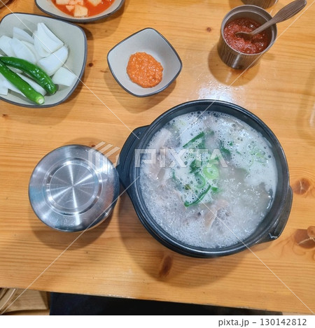 The images show a bowl of steaming dwaeji gukbap, a popular Korean pork soup with rice, served with various side dishes. The images show a bowl of steaming dwaeji gukbap, a popular Korean pork soup with rice, served with various side dishes. 130142812