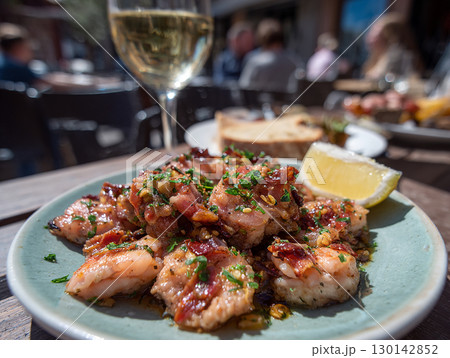 Grilled octopus tapas with garlic and herbs served with lemon wedge and white wine 130142852