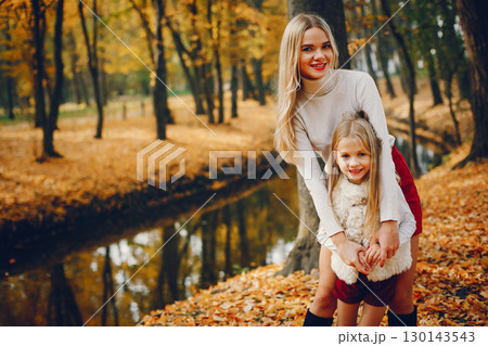Fashionable mother with daughter. Family in a autumn park. 130143543