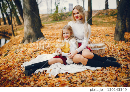 Fashionable mother with daughter. Family in a autumn park. 130143549