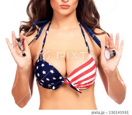 Sexy woman in swimsuit with the USA flag colors holds a stethoscope Sexy woman in swimsuit with the USA flag colors holds a stethoscope 130143591