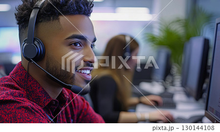 Young African American man wearing a headset is engaged in a customer service role at a modern office, showcasing professionalism and communication skills in a collaborative environment Young African American man wearing a headset is engaged in a customer service role at a modern office, showcasing professionalism and communication skills in a collaborative environment 130144108