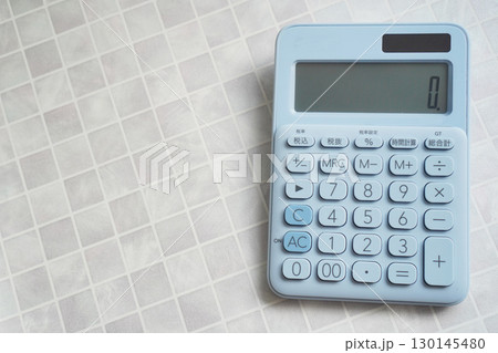 白いタイルの上に置かれたブルーのシンプルな電卓　オフィスと学習の道具 130145480