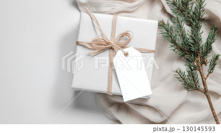 Christmas and New Year mockup of white gift box with blank tag on festive background and copy space, warm color tone. 130145593