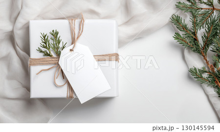 Christmas and New Year mockup of white gift box with blank tag on festive background and copy space, warm color tone. 130145594