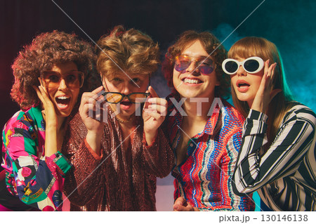 Smiling retro group in bold disco costumes celebrating friendship Smiling retro group in bold disco costumes celebrating friendship 130146138
